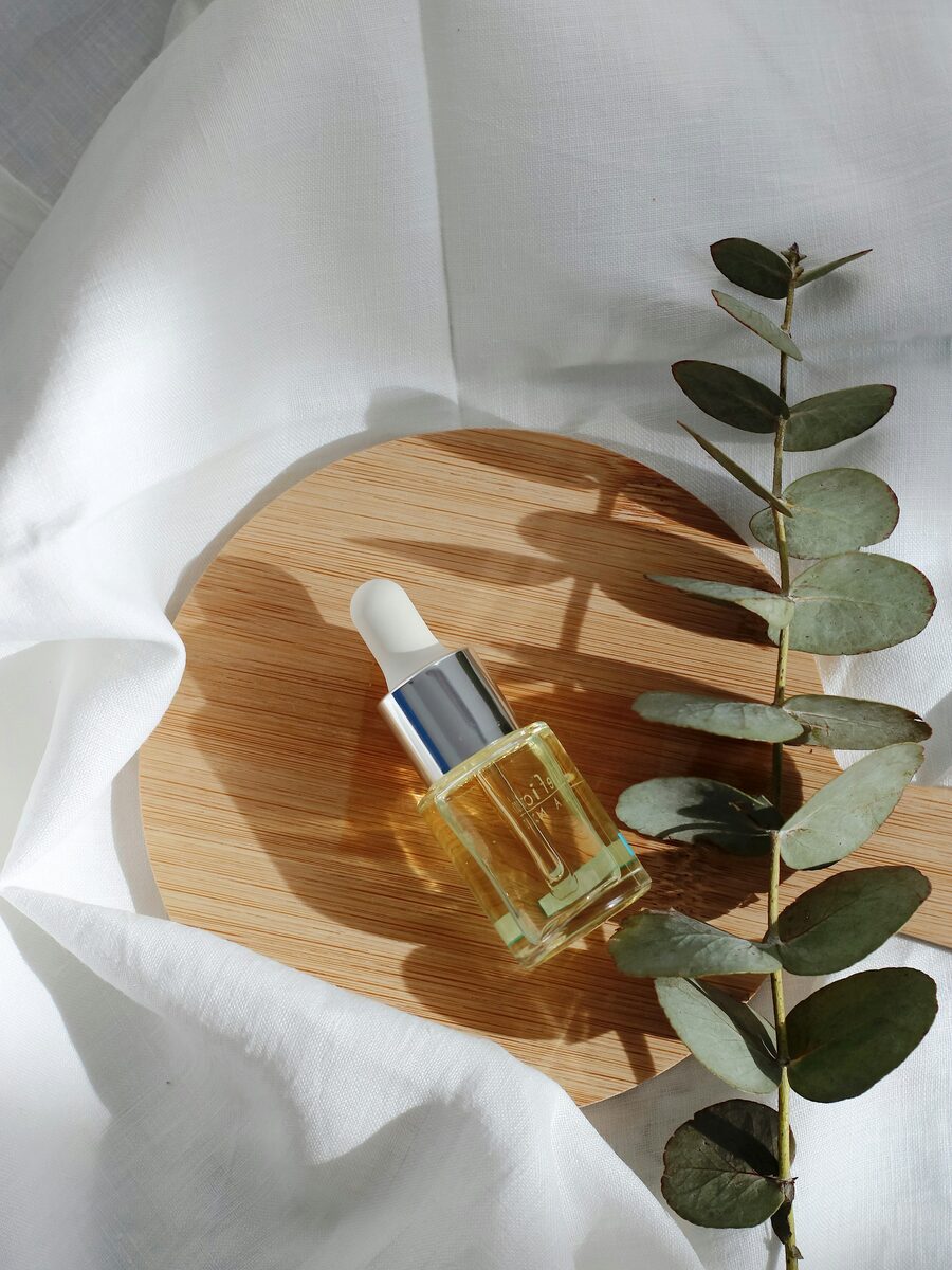 Serum dropper bottle on linen beside eucalyptus